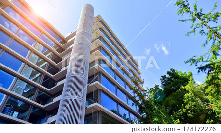 Sustainable glass office building with trees for reducing carbon dioxide. Eco-friendly building in modern city. Office with green environment. Corporate building reduce CO2. 128172276