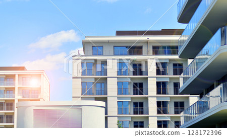 Modern apartment buildings on a sunny day with a blue sky. Facade of a modern apartment building. Modern residential apartment building complex condo. 128172396