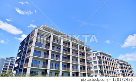 Modern apartment buildings on a sunny day with a blue sky. Facade of a modern apartment building. Modern residential apartment building complex condo. 128172486