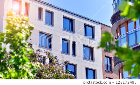 European residential architecture harmonizing with nature. Eco-friendly living in city with greens. Eco apartment building saving energy and fresh air concept. European residential architecture harmonizing with nature. Eco-friendly living in city with greens. Eco apartment building saving energy and fresh air concept. 128172493