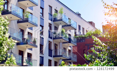 European residential architecture harmonizing with nature. Eco-friendly living in city with greens. Eco apartment building saving energy and fresh air concept.  128172499