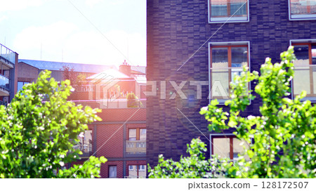 European residential architecture harmonizing with nature. Eco-friendly living in city with greens. Eco apartment building saving energy and fresh air concept. European residential architecture harmonizing with nature. Eco-friendly living in city with greens. Eco apartment building saving energy and fresh air concept. 128172507
