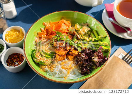 Soft boiled eggs served with toast and pesto with avocado and red onion, served on a beautiful blue and white plate. A breakfast set illuminated by the morning sun. 128172713
