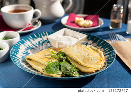 Pancakes with spinach and Greek yogurt served on a beautiful blue and white plate. A breakfast set illuminated by the morning sun. Pancakes with spinach and Greek yogurt served on a beautiful blue and white plate. A breakfast set illuminated by the morning sun. 128172757