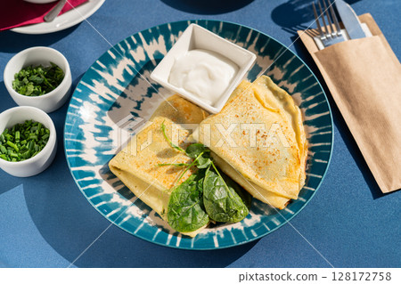 Pancakes with spinach and Greek yogurt served on a beautiful blue and white plate. A breakfast set illuminated by the morning sun. Pancakes with spinach and Greek yogurt served on a beautiful blue and white plate. A breakfast set illuminated by the morning sun. 128172758