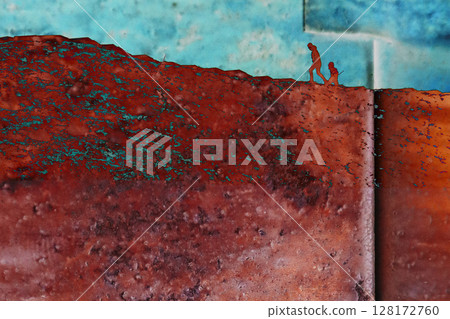 Silhouettes of people, an adult and a child, climbing to the top of a hill on a blue sky rusty background. Travel concept. Climb up the mountain hills 128172760