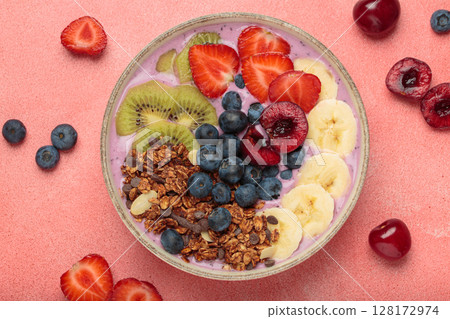 Delicious acai bowl with fresh fruits and granola in white ceramic bowl on pink table top view, healthy breakfast or snack Delicious acai bowl with fresh fruits and granola in white ceramic bowl on pink table top view, healthy breakfast or snack 128172974