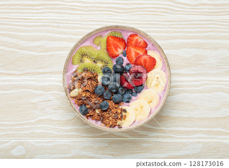 Delicious acai bowl with fresh fruits and granola in white ceramic bowl on white wooden table top view, healthy breakfast or snack Delicious acai bowl with fresh fruits and granola in white ceramic bowl on white wooden table top view, healthy breakfast or snack 128173016