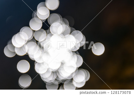 Delicate white light bokeh shapes gently blurred against a dark background, Delicate white light bokeh shapes gently blurred against a dark background, 128173078