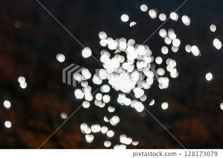Abstract blurred bokeh lights creating a sparkling pattern over a dark surface 128173079