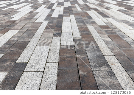 Urban paved outdoor surface displays a pattern of interlocking brickwork tiles 128173086