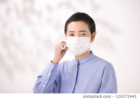 Middle-aged woman removing mask Middle-aged woman removing mask 128173441