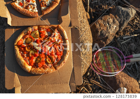 Italian pizza lies on table on paper box on beach in summer 128173839