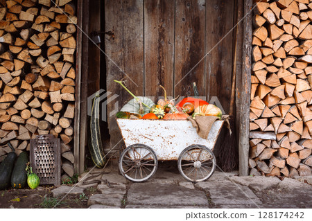 Old cart filled with various pumpkins placed beside rustic barn Old cart filled with various pumpkins placed beside rustic barn 128174242
