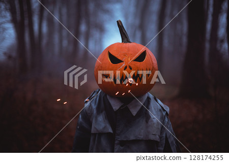Spooky figure with pumpkin head smoking with smoke and sparks Spooky figure with pumpkin head smoking with smoke and sparks 128174255