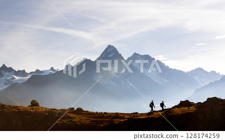 Two hikers walking above Lac de Cheserys in the French Alps 128174259