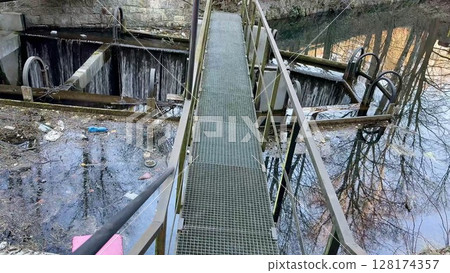 Bridges and Reflective Water Surfaces Captured in an Abandoned Industrial Location Setting Bridges and Reflective Water Surfaces Captured in an Abandoned Industrial Location Setting 128174357