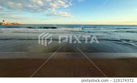 Experience the beautiful ambiance of serene beach waves at sunset, where nature meets tranquility 128174372