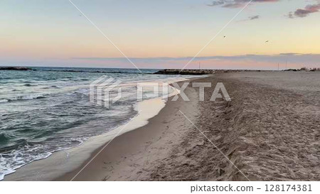 A Tranquil Beach at Sunset, with Gentle Waves Lapping at the Shore, Creating Serenity 128174381