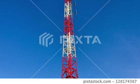 A tall communication tower standing against a clear blue sky, showcasing modern technology 128174387