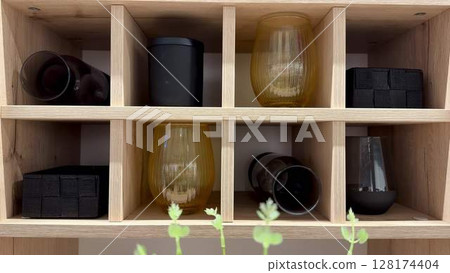 Stylish Glasses and Containers Expertly Organized on a Beautiful Wooden Shelf Display 128174404