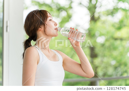 Young Asian woman drinking mineral water in the park/forest 128174745