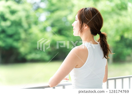 Back view of a young woman in sportswear looking outside in a forest or park Back view of a young woman in sportswear looking outside in a forest or park 128174769