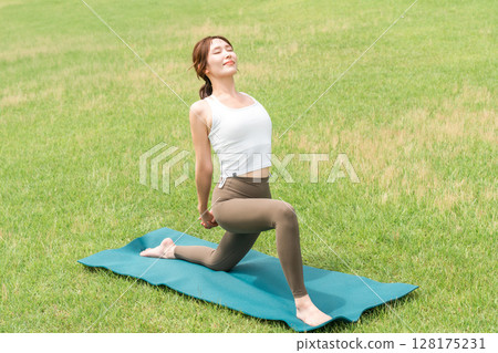 Young Asian woman doing park yoga, yoga pilates stretching in the park 128175231