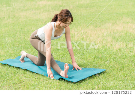 Young Asian woman doing park yoga, yoga pilates stretching in the park Young Asian woman doing park yoga, yoga pilates stretching in the park 128175232