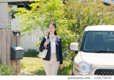 一名身穿西裝的女子站在一輛汽車旁 一名身穿西裝的女子站在一輛汽車旁 128175670