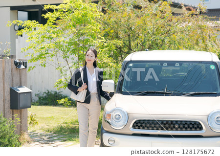 一名身穿西裝的女子站在一輛汽車旁 一名身穿西裝的女子站在一輛汽車旁 128175672