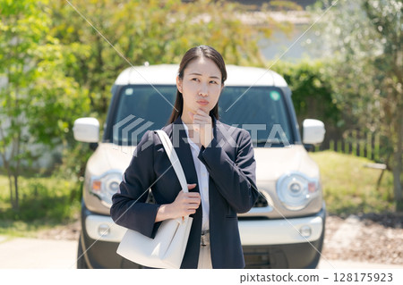 A woman with a worried expression in front of a car A woman with a worried expression in front of a car 128175923