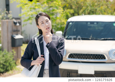 一名女子站在車前,一臉憂慮 一名女子站在車前,一臉憂慮 128175926