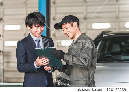 Mechanic and front man in the pit of a repair shop (diagnosis, maintenance, computer diagnosis) 128176389