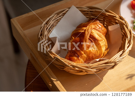 Close up of plain croissants served on wooden table. Croissant is a French buttery, flaky and crescent-shaped bread. Close up of plain croissants served on wooden table. Croissant is a French buttery, flaky and crescent-shaped bread. 128177189