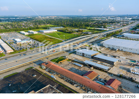 Complex multi level highway intersection with industrial warehouses, parking lots, surrounding suburban landscape in Houston, Harris County, Texas. 128177266