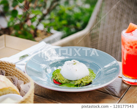Buratta cheese salad with avocado cream base in blue rustic plate in restaurant or cafe table. Burratina fresh healthy meal food snack diet on wooden table in summer sunny day outdoor, copy space 128177543
