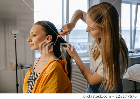 Hairdresser Styling Woman's Long Hair in Salon Hairdresser Styling Woman's Long Hair in Salon 128177676