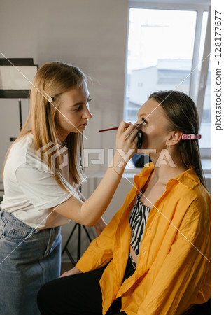 Makeup Artist Applying Foundation to Client in Salon 128177677