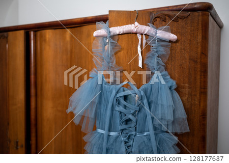 Elegant Blue Tulle Dress Hanging on Wooden Wardrobe 128177687