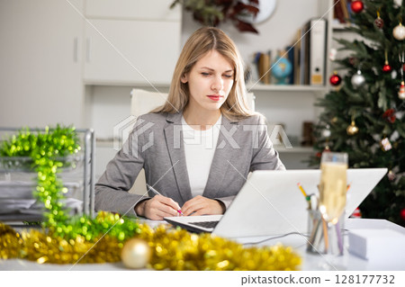 Woman bookkeeper doing paperwork in Christmas decorated office 128177732