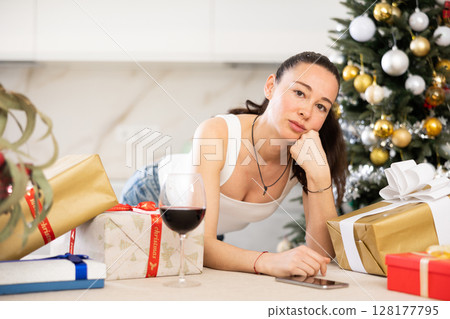 pensive young girl stands among New Year s gifts pensive young girl stands among New Year s gifts 128177795