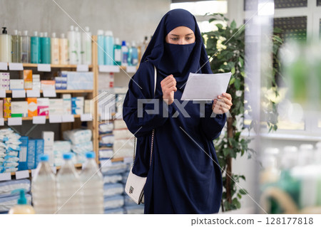 Young woman in hijab chooses prescription medications 128177818