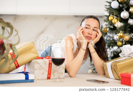 pensive young girl stands among New Year s gifts 128177842