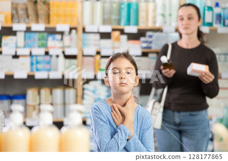 Adult woman chooses medicine for her coughing daughter 128177865
