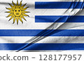 Uruguay Flag Waving on Fabric with Sun Emblem and Blue Stripes 128177957