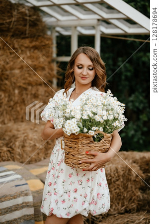 Woman Holding Basket of Flowers in Rustic Setting 128178694