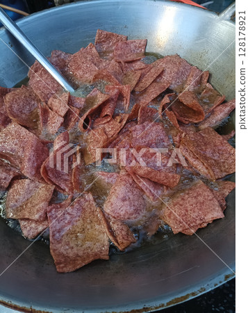 Crispy fried meat slices cooking in large pan, sizzling with oil, creating savory aroma and golden brown color, perfect for flavorful meal or snack Crispy fried meat slices cooking in large pan, sizzling with oil, creating savory aroma and golden brown color, perfect for flavorful meal or snack 128178921