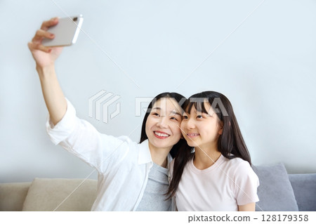 Image of a mother and daughter taking a selfie with a smartphone Image of a mother and daughter taking a selfie with a smartphone 128179358