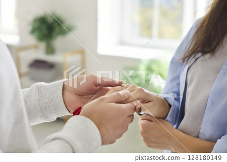 Guy puts diamond engagement ring on his girlfriends finger during marriage proposal. 128180149